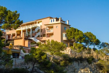 Alçak Doğulu Tatil Tatil Oteli 'nin Mimarisi Uçuruma tünemiş ve çevresi Berrak Yeşil Ağaçlarla çevrili Gün batımında Ilık Gün Işığıyla aydınlanan Açık Mavi Gökyüzü