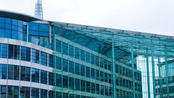 Architectural Close Up of Modern Low Rise Office Building with Transparent Glass Facade on Overcast Day with Gray Sky