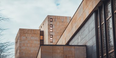 Almanya 'da ağaç dalları ve bulutlarla çerçevelenmiş küp şeklindeki pencereleri olan modern şehir binası