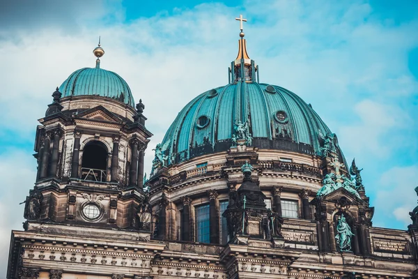 Old Christian church exterior with elegant decorations and umbrella type copper domes under golden crucifix