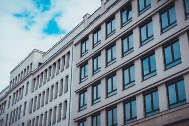 Düşük Yükselen Modern Ofis Binalarının Açılı Mimari Dış Görünümü Tekrar Eden Pencereler ve Bulutlu Mavi Gökyüzü ile Kentsel Ayarlar 'da yan yana