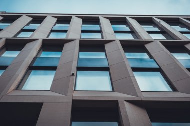 Pencereler ve Mavi Gök 'e Karşı Kahverengi Taş Sütunlu Modern Ticari Düşük Açılı Ofis Binası Görünümü - Soyut Mimari Arkaplan