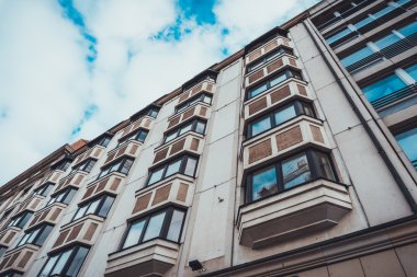 Low Rise Residential Apartman Binası 'nın düşük açılı kapanış pencereli ağır beyaz bulutlu mavi gökyüzüne karşı açılı