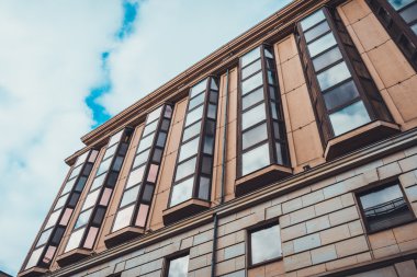 Aşırı Yakın Çekim ve Düşük Açı Konut Görünümü Düşük Kalite Apartman Koyu Pencereli ve Mavi Gök 'e Karşı Kahverengi Taş Cephe Ağır Beyaz Bulutlu