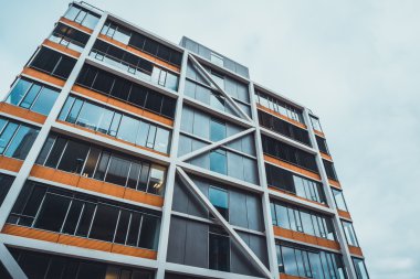 Turuncu çerçeveli ve dış destekli modern konut binasının düşük açılı görüntüsü