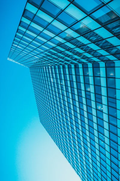 Modern bir ofis bloğunun dış mavi cephesi. Pencereleri sıra sıra, düşük açı perspektifi binanın köşesine bakıyor.