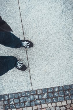 Beton ve tuğla kaldırımda duran kimliği belirsiz bir arkadaşın bacaklarına ve ayaklarına bakan ilk kişi.