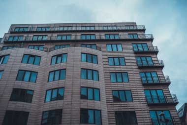Düşük Açı Mimarisi Modern Low Rise Residential Apartmanı veya Brown Stone Facade ve Şehir Kentinde Bulutlu Gökyüzü ile Küçük Köşeli Balkonlar