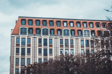 Mimari Dış Görünüm Modern Lüks Konut Apartmanı veya Kırmızı Kiremit Çatılı Apartman ve Önplanda Çıplak Ağaç dalları tarafından gizlenmiş