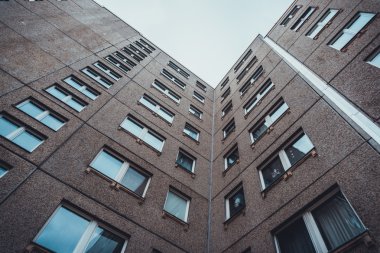 Düşük Açı Mimarisi Orta Yükseliş Konut Apartmanının Kahverengi Taş Yüzlü Binası ve Yinelenen Pencereler Gökyüzüne Doğru azalıyor