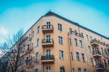 Düşük Açı Mimarisi Modern Low Rise Residential Apartman Binası 'nın Küçük Balkonları ve Çevresi Çıplak Ağaçlar ve Açık Mavi Gökyüzü ile çevrili Berlin, Almanya