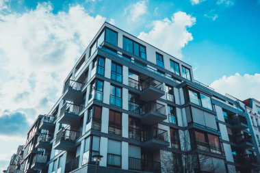 Dairelerdeki cam pencerelerin alçak açılı görüntüsü ve mavi gökyüzünün altında kabarık bulutlu çatı katı.