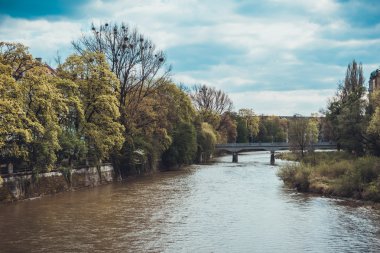 Güzel bir ağaç manzarası, sakin bir nehir uzak bir köprüyü geçiyor.