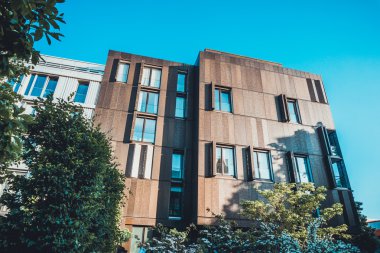 Yeşil ağaçları ve mavi gökyüzü olan modern mimari konağı