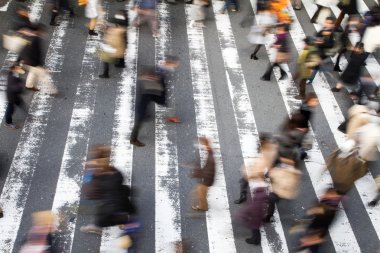 Yaya geçidinde yürüyen kalabalığın yüksek açılı görüntüsü hareket bulanıklığı ve yoldaki çizgilere odaklanma