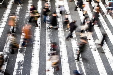 Yürüyen insanlar için hareket bulanıklığı olan bir zebra üzerinde yayalar kalabalığının üzerinden ve asfalttaki çizgilere odaklanın.