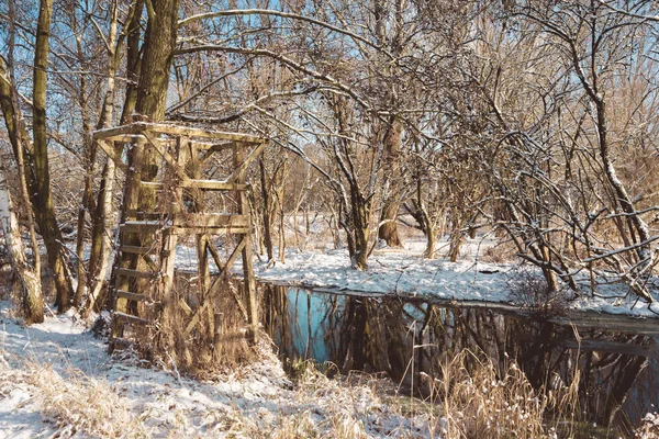 Estructura de madera en la orilla del río en el bosque nevado — Foto de Stock