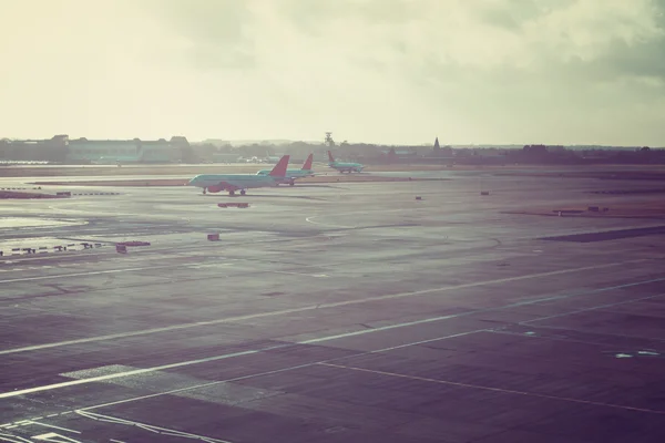 Blue and red commercial passenger jets parked on large airport runway under hazy skies