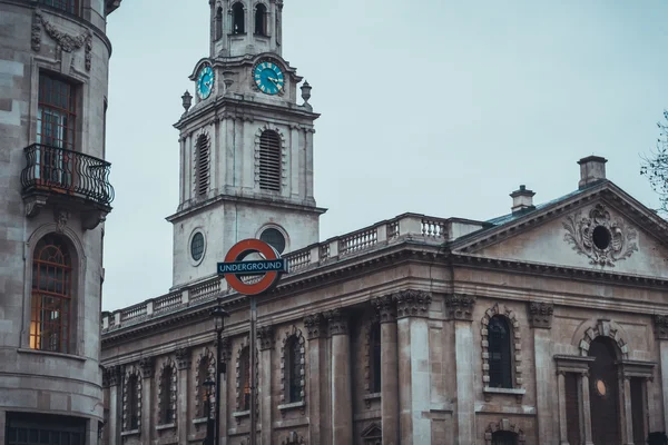 Большой красный знак лондонского метро возле церкви — стоковое фото