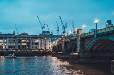 Southwark Köprüsü, Londra Skyline 'ın önündeki Street Lights ve Spanning Ames Nehri ile aydınlandı. İnşaat Vinçleri Bulutlu Akşam, Londra, İngiltere, Uk