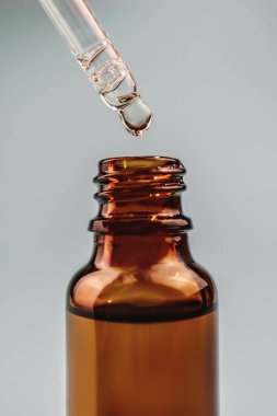 Kahverengi bir şişenin üzerinde kozmetik yağlı bir boru.