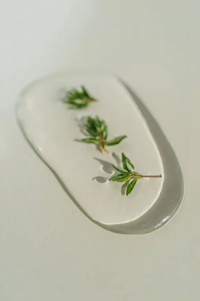A drop of cosmetic gel with thyme on a green background. — Stock Photo, Image