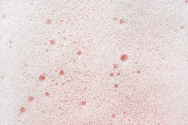 La textura de la espuma de jabón con burbujas sobre un fondo rosa. —  Fotos de Stock