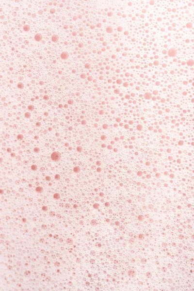 La textura de la espuma de jabón con burbujas sobre un fondo rosa. —  Fotos de Stock