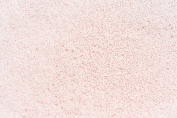 The texture of soap foam with bubbles on a pink background. — Stock Photo, Image