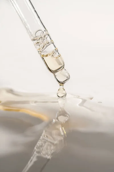 Pipetten bir damla kozmetik yağı düşüyor.