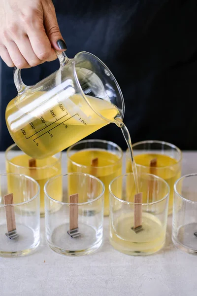 Kız fitilli cam bardaklara balmumu döküyor..