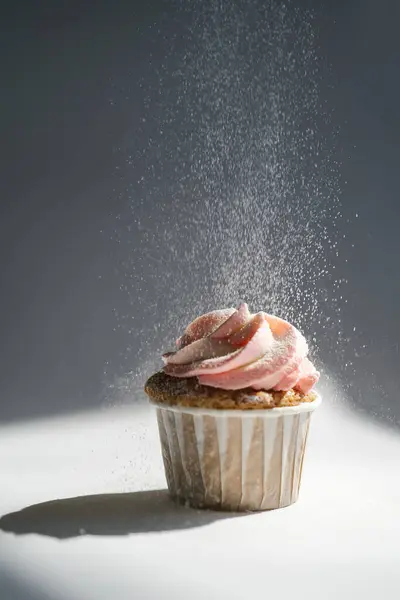 Cupcake on a dark background, which is sprinkled on top. — Stock Photo, Image