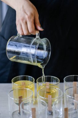 Kız fitilli cam bardaklara balmumu döküyor..