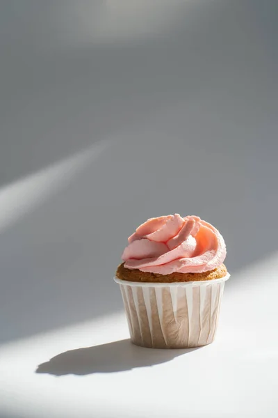 Cupcake on a white sunny background with a shadow. — Stock Photo, Image