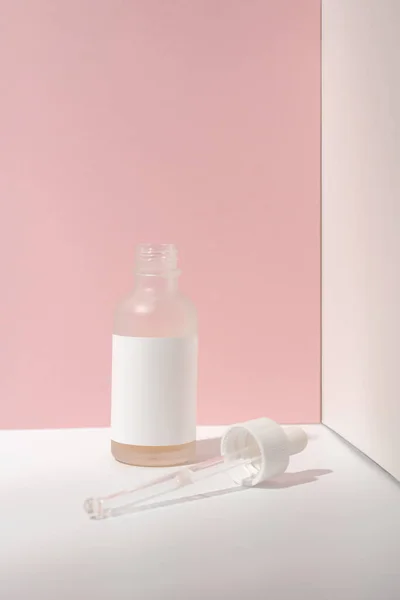 Beyaz-pembe arka planda göz damlası olan kozmetik şişesi..