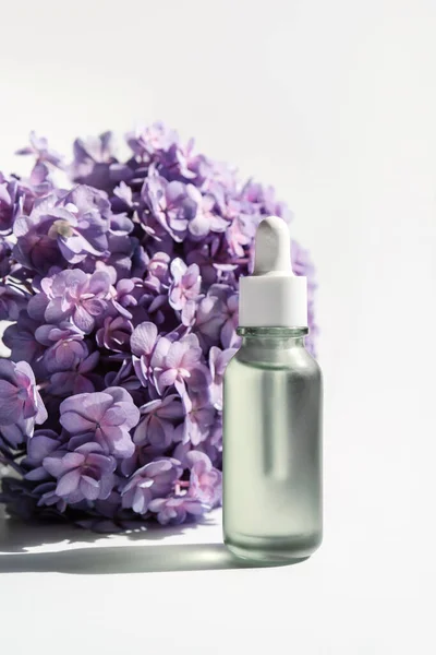 Beyaz arka planda kozmetik şişesi ve çiçekler.