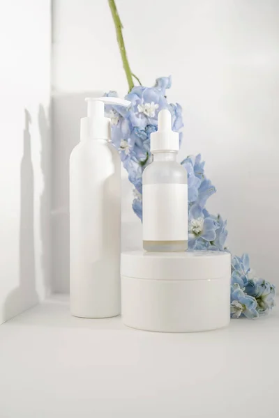 Beyaz arka planda kozmetik şişeleri ve çiçekler.