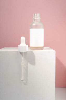 Beyaz-pembe arka planda göz damlası olan kozmetik şişesi..