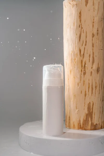 Butelka kosmetyczna z rozpryskami wody na szarym tle. — Zdjęcie stockowe