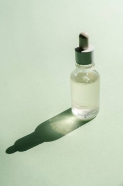 Yeşil arka planda duran bir şişe serum..