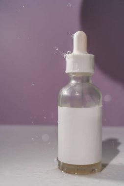 Mor arka planda su sıçraması olan kozmetik şişeleri..