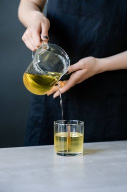 Kız fitilli cam bardaklara balmumu döküyor..