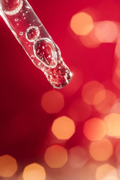 Pipetta con siero su sfondo rosso vacanza con bokeh. — Foto Stock