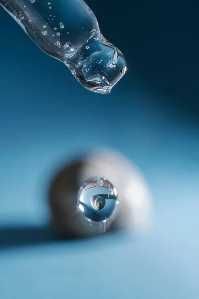 Pipette with transparent serum on the background of shells.