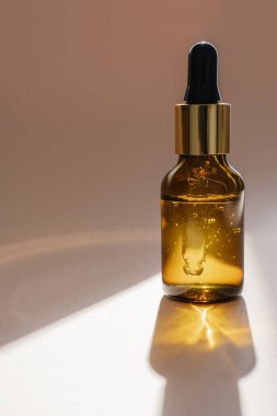 Bej arka planda kahverengi bir serum şişesi..