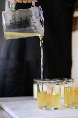 Kız fitilli cam bardaklara balmumu döküyor..