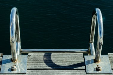 GLOSSY METAL LADDER EMPTYING INTO THE SEA