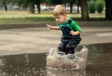 Çocuk su birikintilerinde yürüyor.