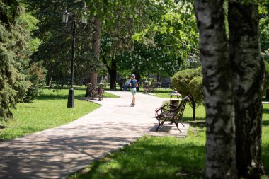 Çocuk parkta scooter sürüyor.