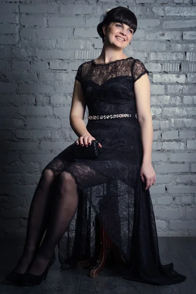 A girl sits on a chair in a black dress — Stock Photo, Image